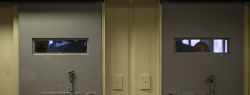Inmates peer through the windows behind cell doors inside the Worcester County jail. (Jesse Costa/WBUR)